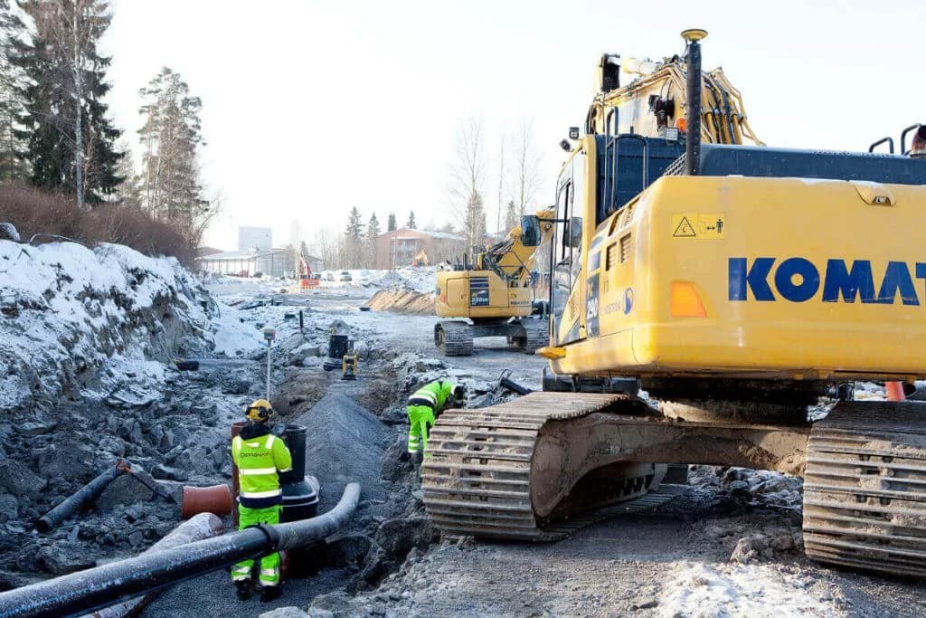 Mättekniker och grävmaskin vid ett ledningsschakt vintertid