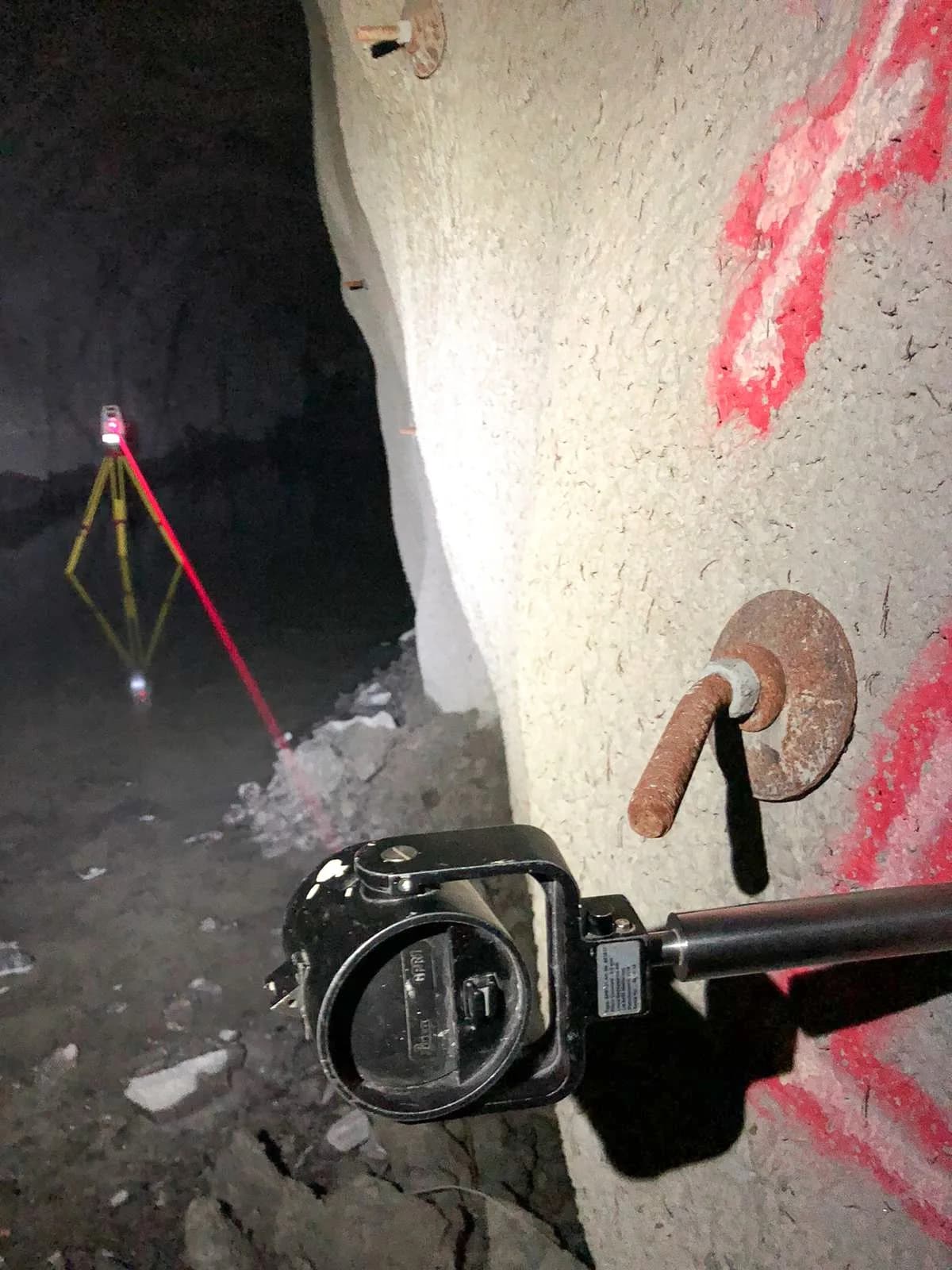 Totalstation uppställd i en tunnel med markeringar på berget