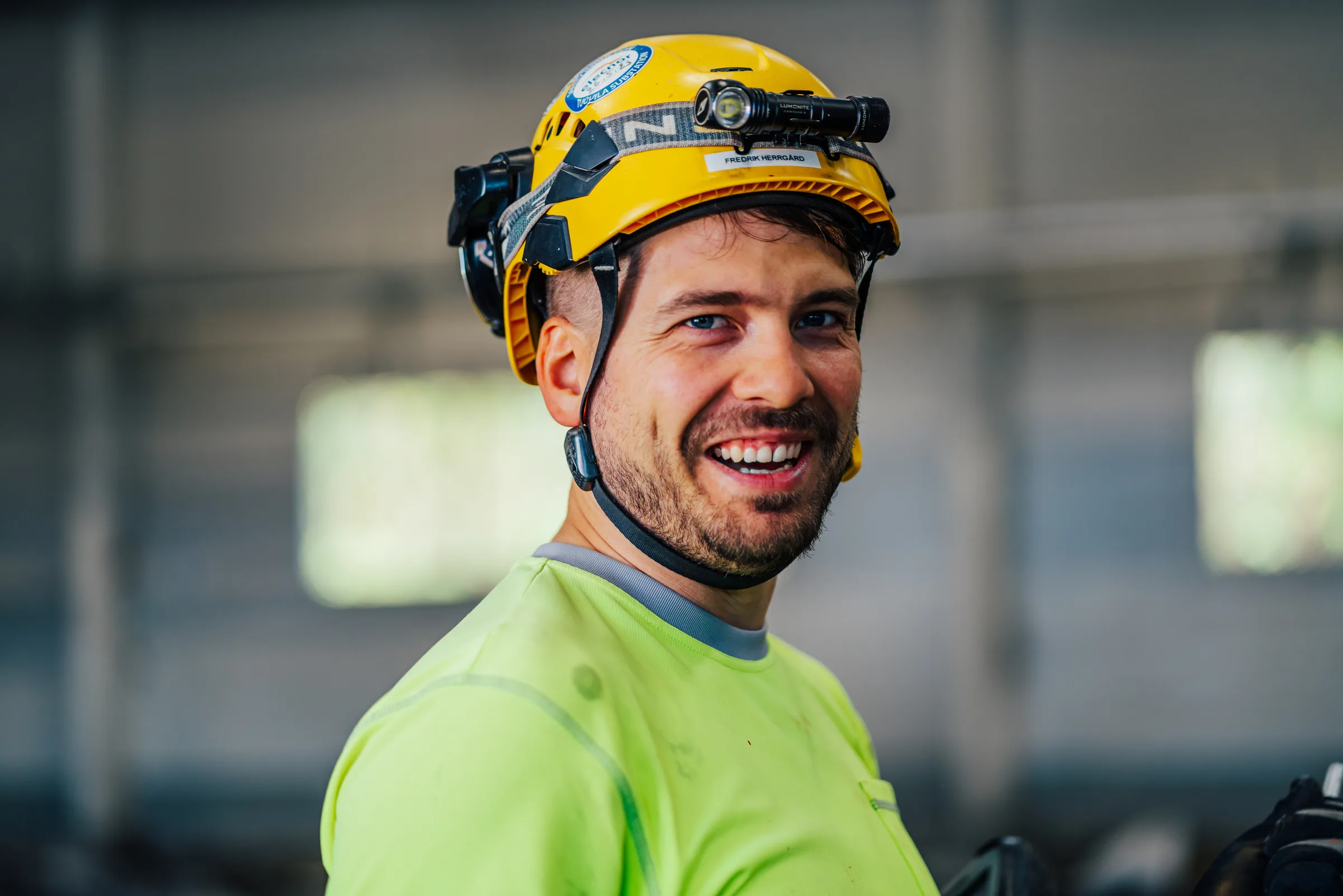 Smiling surveyor wearing a yellow helmet and headlamp