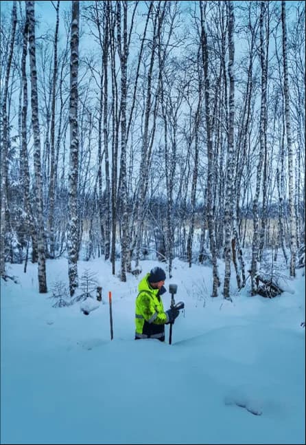 Mättekniker med GNSS-utrustning bland björkar i snön